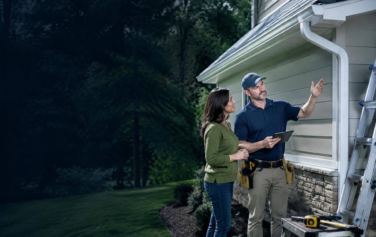 Gutter specialist speaking with a homeowner beside a gutter installation
